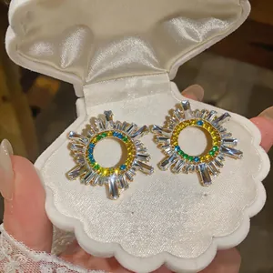 Primo piano dettagliato di orecchini vintage a raggiera con strass colorati in scatola a conchiglia