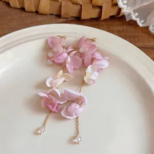 Detailed macro shot of elegant pink floral tassel earrings placed on a white ceramic plate