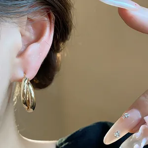 Detail shot of 18K gold plated triple hoop earrings worn for a minimalist luxury look