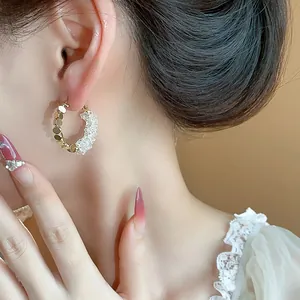 Detailed close-up of 14K gold plated silver needle crystal hoop earrings on model ear