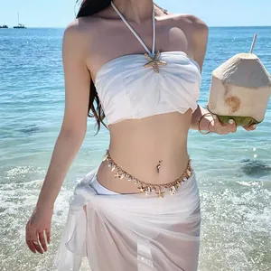 Detail of bohemian gold waist chain with seashell and starfish charms on a model