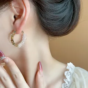 Detailed close-up of 14K gold plated hoop earrings featuring crystals and gold sequins