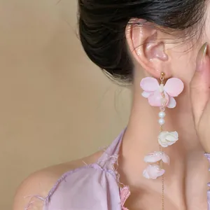 Detailed close-up showing elegant long pink fabric flower tassel earrings with pearls.