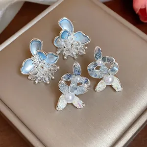 Macro view showing the intricate detail of elegant blue glass flower and pearl stud earrings