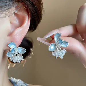 Close-up of elegant blue enamel flower earrings with sparkling glass bead clusters