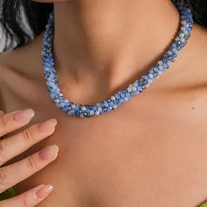Close-up of elegant blue and grey faceted crystal beaded twisted necklace on model.
