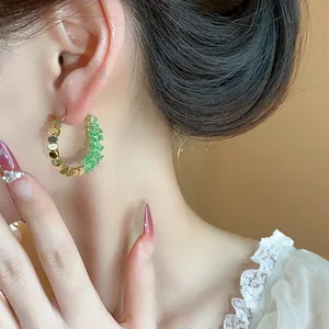 Close-up of 14K gold plated crystal hoop earrings with crushed gold and green crystals