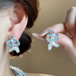 Macro view of delicate flower-shaped earrings with pearl accents and glass petals
