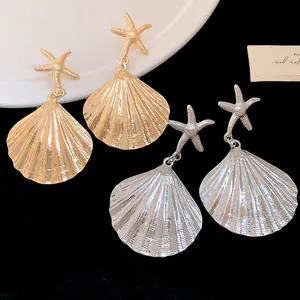 Detailed macro shot of elegant gold and silver metal pleated shell earrings with starfish studs