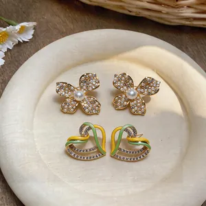Detailed shot of gold earrings with floral and heart shapes, pearls, and sparkling crystals.