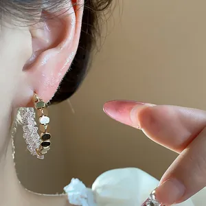 Close-up of 14K gold plated crystal hoop earring on ear showing sparkling detail.