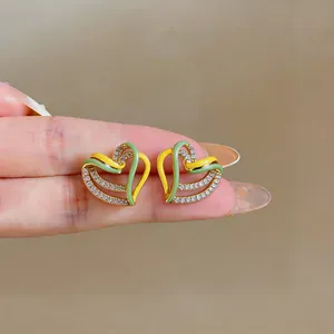 Detailed view of layered heart stud earrings with yellow green enamel and zircons