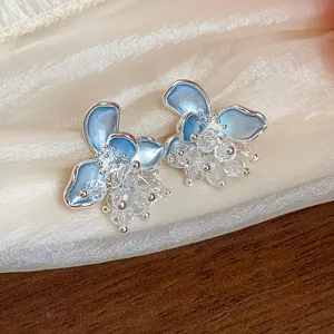 Detail of light blue enamel floral stud earrings featuring elegant crystal centers