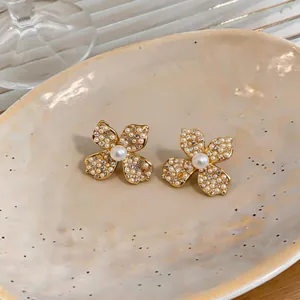 Close-up of elegant flower stud earrings with pavé zircons and faux pearls.