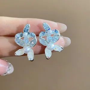 Detailed close-up of elegant floral silver stud earrings featuring glass crystals and white pearls