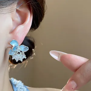 Close-up detail showing a blue glass flower earring with silver needle and pearls