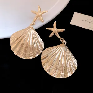 Close-up of gold metal starfish and pleated shell earrings on black background