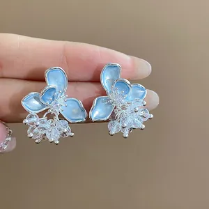 Close-up of elegant blue enamel flower earrings with clear crystal bead clusters