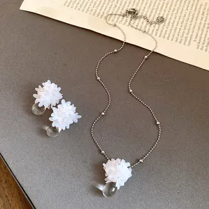 Vue détaillée du collier et des boucles d'oreilles fleurs à paillettes et gouttes.