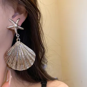 Detailed macro view of metallic pleated shell earring with a starfish stud accessory