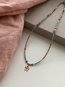 Close-up detail of vintage bohemian beaded necklace with a delicate golden flower pendant