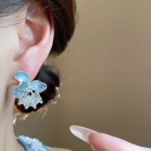 Detailed close-up view of light blue glass flower earrings with dangling crystals