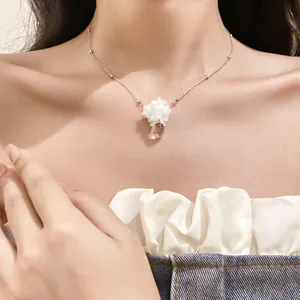 Gros plan d'un délicat collier avec pendentif fleur et goutte d'eau sur un mannequin.