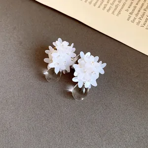 Gros plan de boucles d'oreilles fleurs en paillettes blanches avec gouttes d'eau