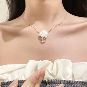 Détail en gros plan d'un collier à fleurs blanches et pendentif goutte d'eau claire
