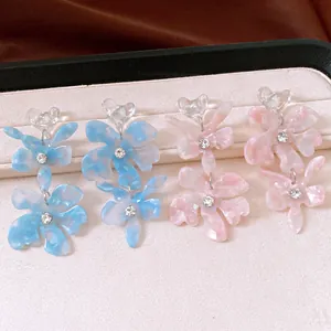 Macro view showing the detailed texture of acrylic flower tassel earrings with rhinestones.