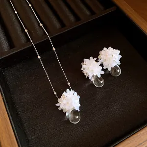 Vue détaillée du collier et des boucles d'oreilles fleur à paillettes et goutte d'eau claire