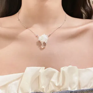 Vue détaillée du collier pendentif fleur blanche avec goutte d'eau claire sur le cou.