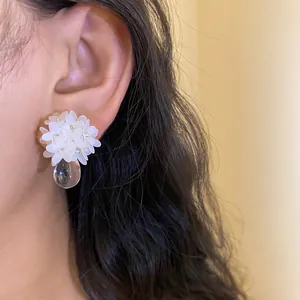 Gros plan de boucles d'oreilles fleurs en paillettes blanches avec goutte d'eau