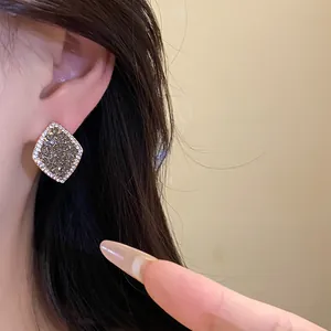 Elegante rautenförmige Pavé-Ohrringe im Detail, getragen von einem Modell für Schmuckdesign.