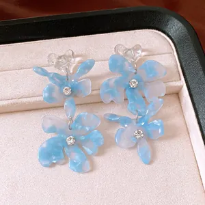 Close-up detail of elegant blue marble effect flower earrings with sparkling crystals