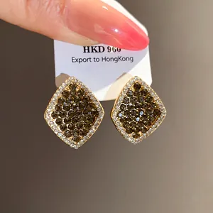 Detaillierte Nahaufnahme eleganter goldener Rautenohrstecker mit grauen Kristallen