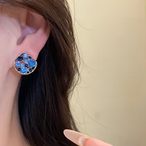 Detailansicht eleganter Silberohrringe mit blauen Strasssteinen direkt am Ohr