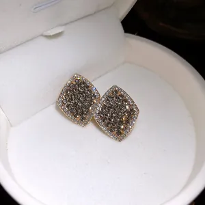 Nahaufnahme eleganter goldfarbener Rauten-Ohrstecker mit Pavé-Kristallen