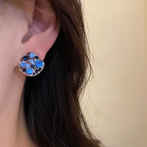 Nahaufnahme eleganter rautenförmiger Ohrstecker mit funkelnden blauen Diamanten