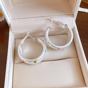 Detail of brushed silver hoop earrings featuring colorful dopamine polka dots in a gift box