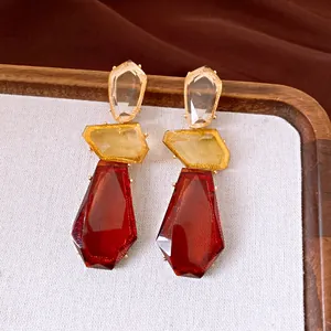 Detaillierte Ansicht unregelmäßiger geometrischer Harzohrringe in den Farben Rot und Gelb.