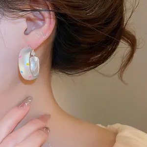 Close-up of vibrant dopamine colorful polka dot brushed silver hoop earring worn on model's ear