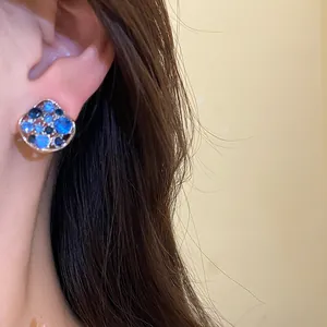 Eleganter Silberohrstecker mit blauen Strasssteinen am Ohr in einer Detailaufnahme