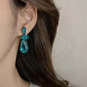 Elegante blaugrüne unregelmäßige geometrische Harzohrstecker an einem Modell für Stil