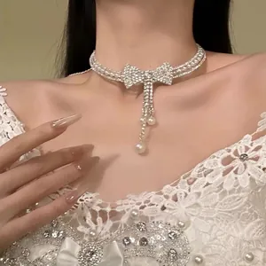 Close-up of sparkling rhinestone bow and pearl choker on model for evening wear