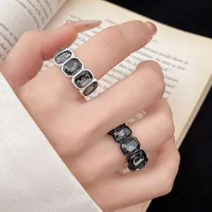 Dettaglio di anelli aperti esagonali vintage con strass grigio scuro sulle dita.
