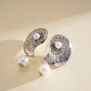 Detailed shot of silver nautilus stud earrings with elegant white pearl accents.