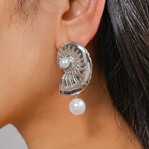 Detailed close-up showing the metallic shell texture and white pearls on this silver earring