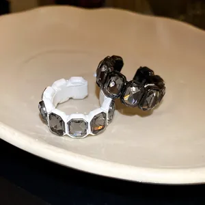 Dettaglio di anelli aperti esagonali con eleganti strass grigi su piatto di ceramica