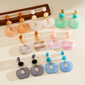 Detailed view of colorful acrylic geometric oval drop earrings on a minimalist background